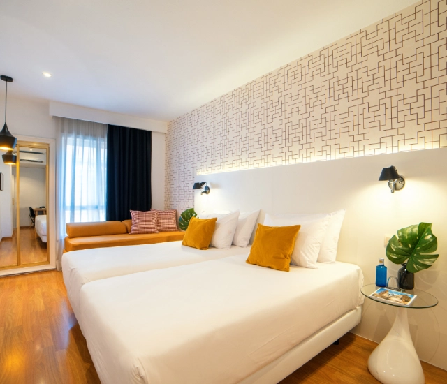 Dormitorio moderno con cama doble, cojines amarillos y pared decorativa.