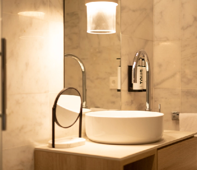 Baño moderno con lavabo redondo y espejo.