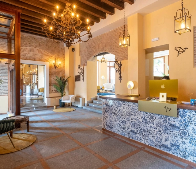 Vest&iacute;bulo de hotel elegante con candelabros y mostrador decorativo.