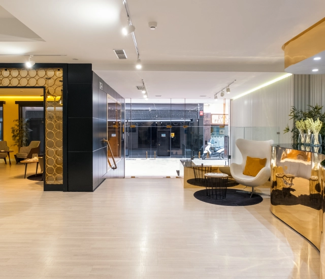 Recepci&oacute;n moderna con sill&oacute;n blanco y mostrador dorado.