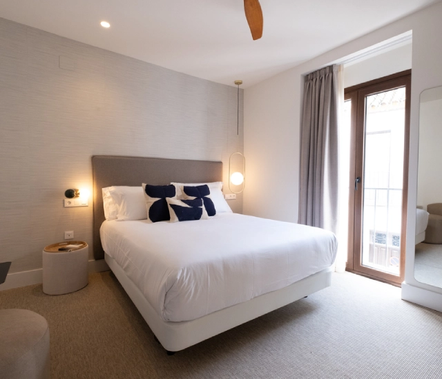 Dormitorio moderno con cama doble, ventana grande y decoraci&oacute;n minimalista.
