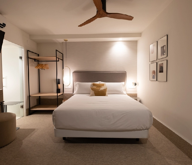 Habitación moderna con cama doble, ventilador y arte en la pared.