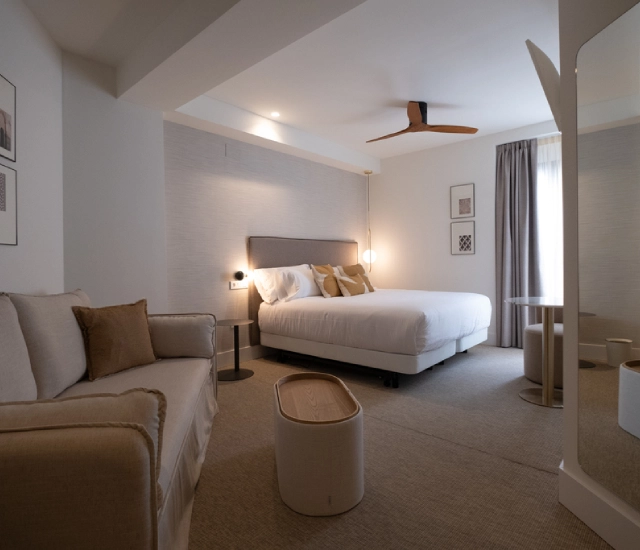 Habitaci&oacute;n moderna con cama doble, sof&aacute; y decoraci&oacute;n minimalista.
