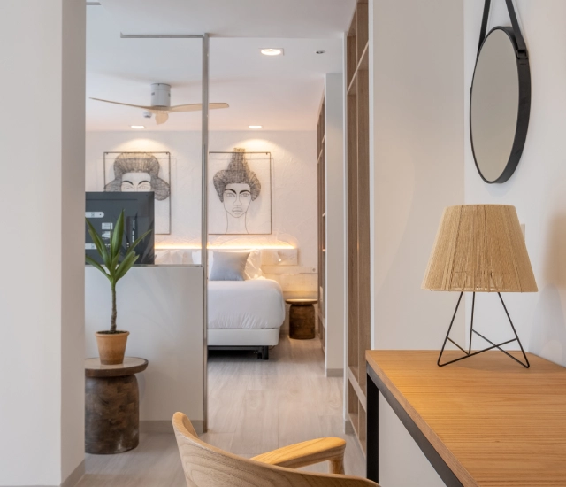 Habitaci&oacute;n moderna con cama, escritorio y l&aacute;mpara decorativa.