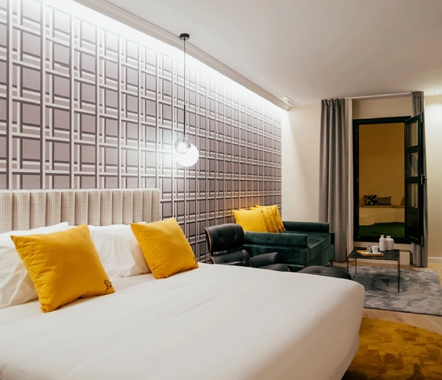 Habitaci&oacute;n moderna con cama doble, cojines amarillos y decoraci&oacute;n minimalista.