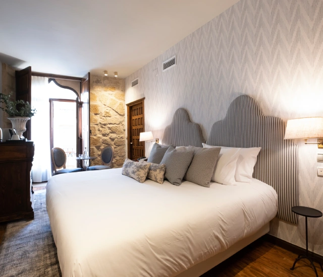 Habitaci&oacute;n de hotel elegante con cama grande y ventana luminosa.