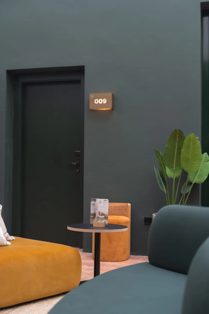 Sala moderna con sillones y planta, puerta con número 009.