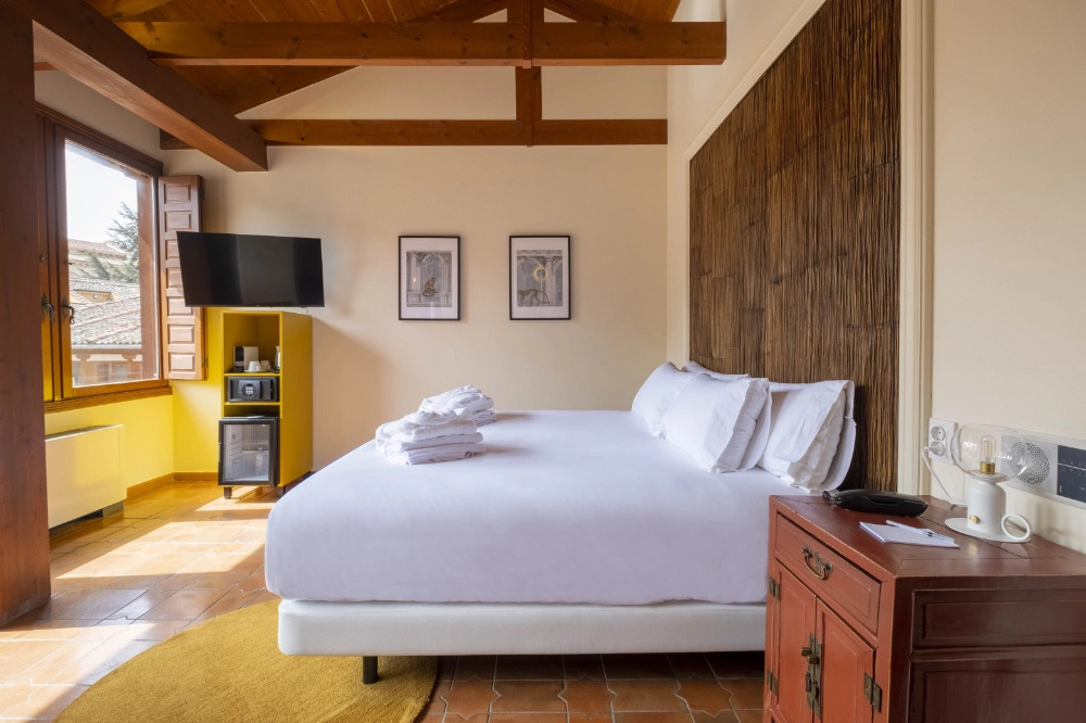 Habitación acogedora con cama doble, TV y ventana; decoración rústica y moderna.