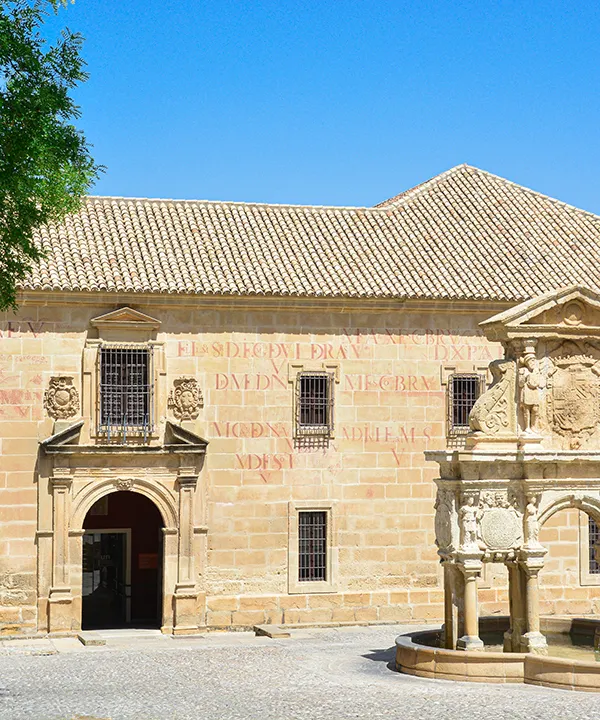 Edificio hist&oacute;rico con fuente en un patio, bajo un cielo despejado.