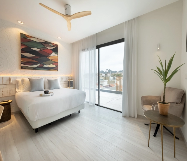Dormitorio minimalista con cama doble, arte en la pared y gran ventanal.