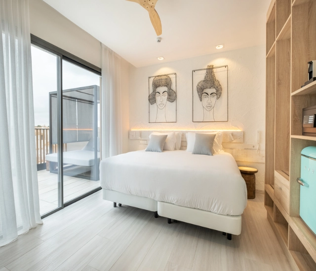 Habitaci&oacute;n moderna con cama doble, obras de arte y balc&oacute;n con vista.