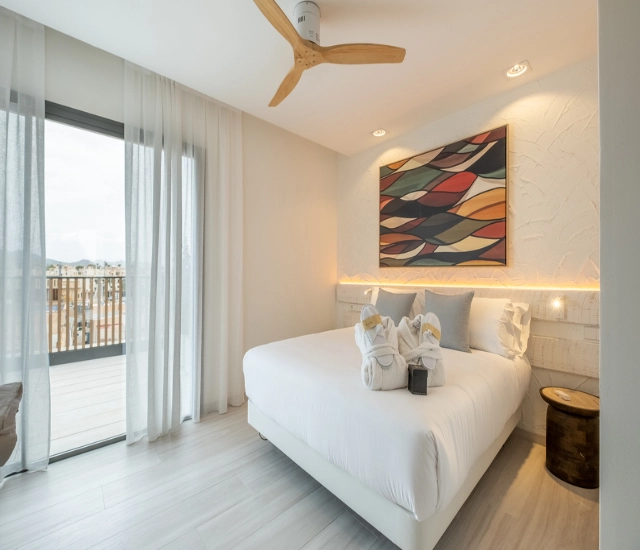 Dormitorio moderno y luminoso con cama, ventana y decoraci&oacute;n colorida.