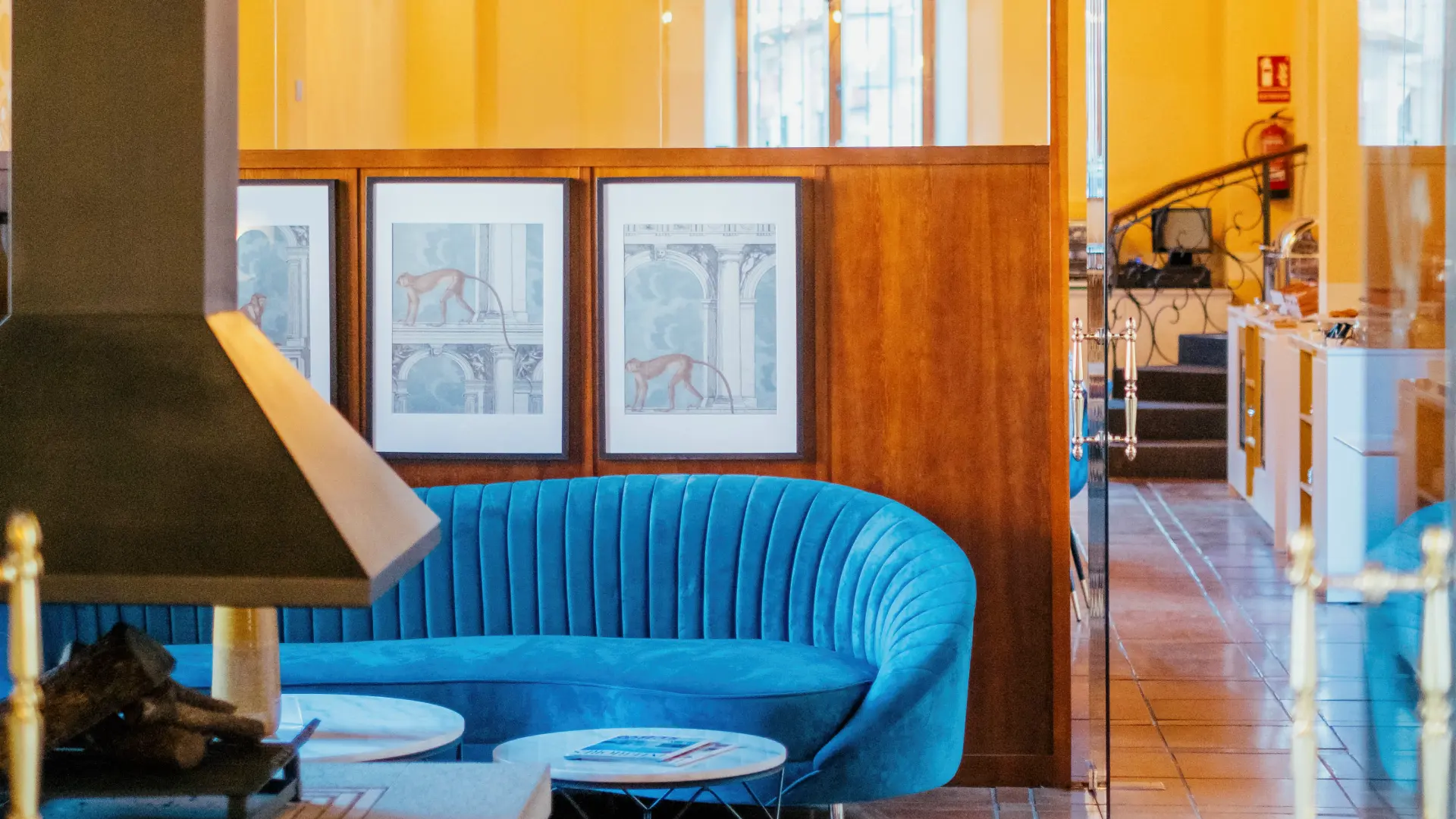 Sofá azul en sala con ilustraciones de monos y paredes de madera.