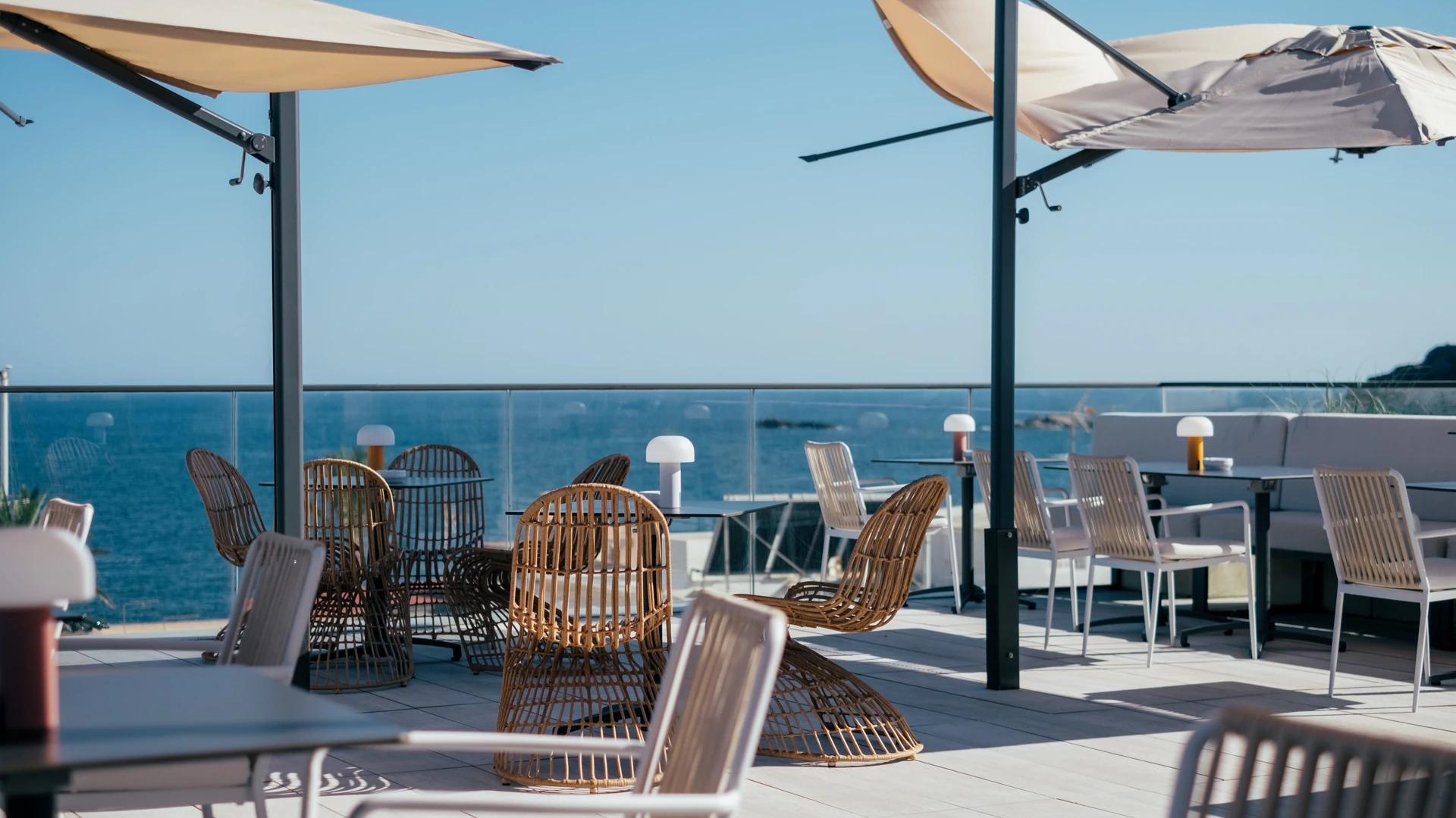 Terraza al aire libre con sillas y sombrillas, vista al mar.