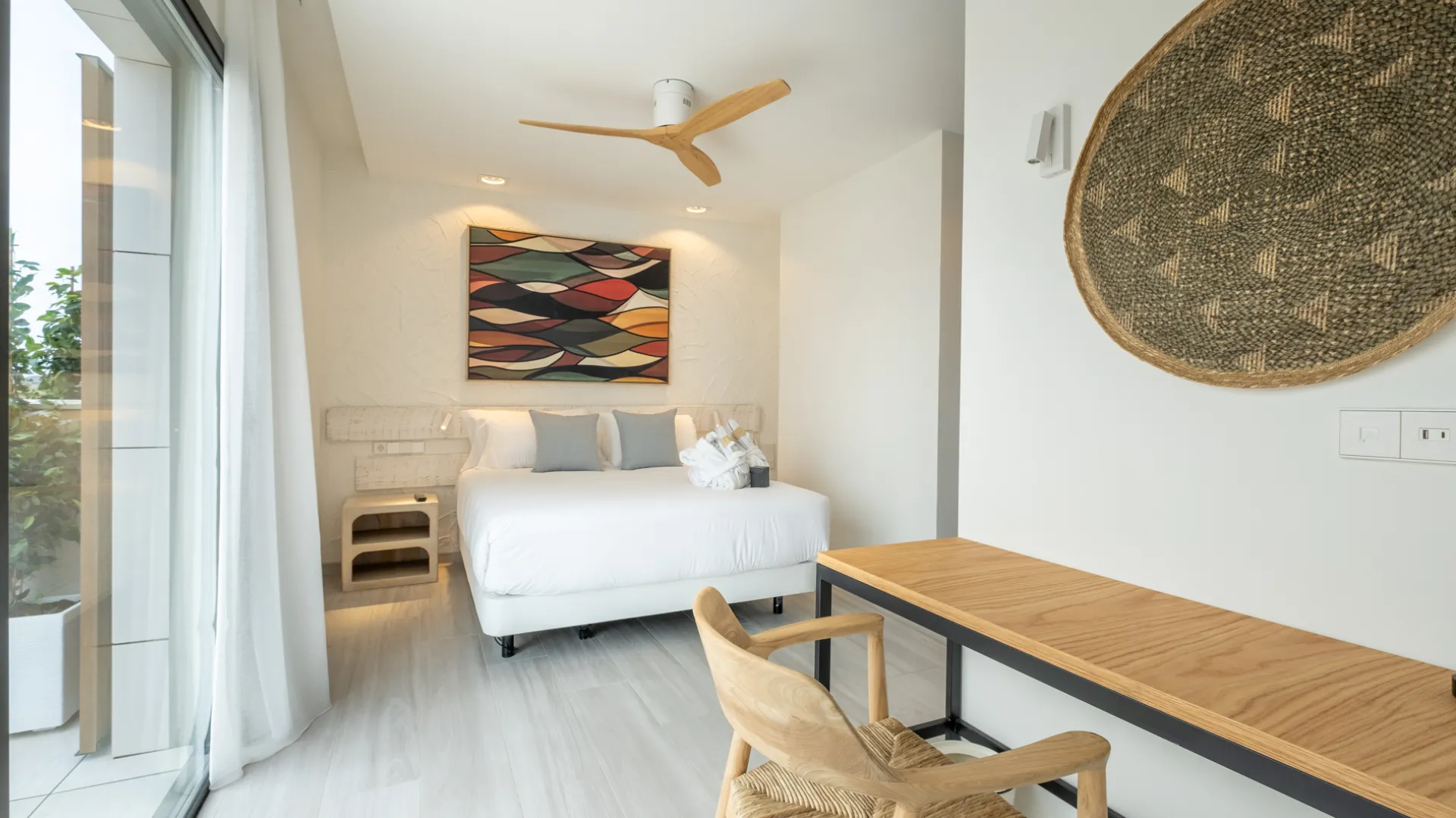 Habitación moderna con cama, escritorio y decoración colorida en la pared.