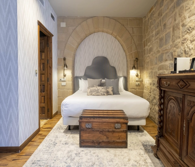 Habitaci&oacute;n con cama doble, ba&uacute;l al pie y decoraci&oacute;n r&uacute;stica.