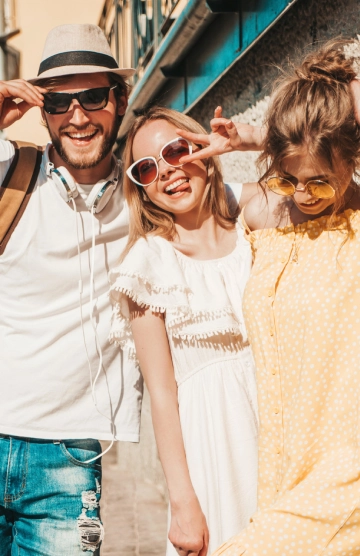 Tres amigos sonrientes con gafas de sol posan al aire libre en verano.
