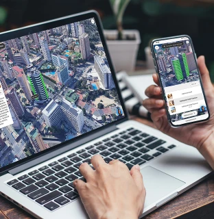 Persona usando mapas en una laptop y un tel&eacute;fono m&oacute;vil.