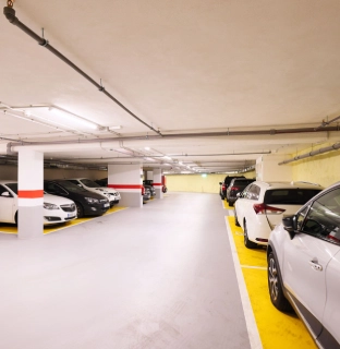 Estacionamiento subterr&aacute;neo con varios autos aparcados.