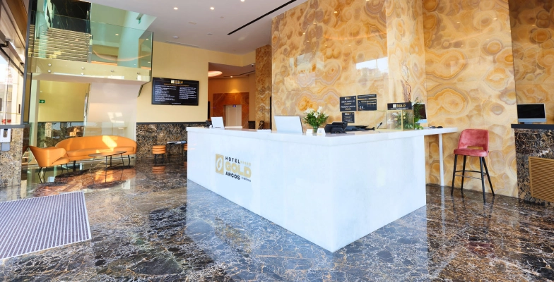 Recepci&oacute;n de hotel con mostrador blanco y suelos de m&aacute;rmol. Decoraci&oacute;n moderna.
