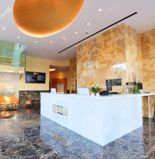 Recepci&oacute;n de hotel con dise&ntilde;o moderno y suelo de m&aacute;rmol oscuro brillante.