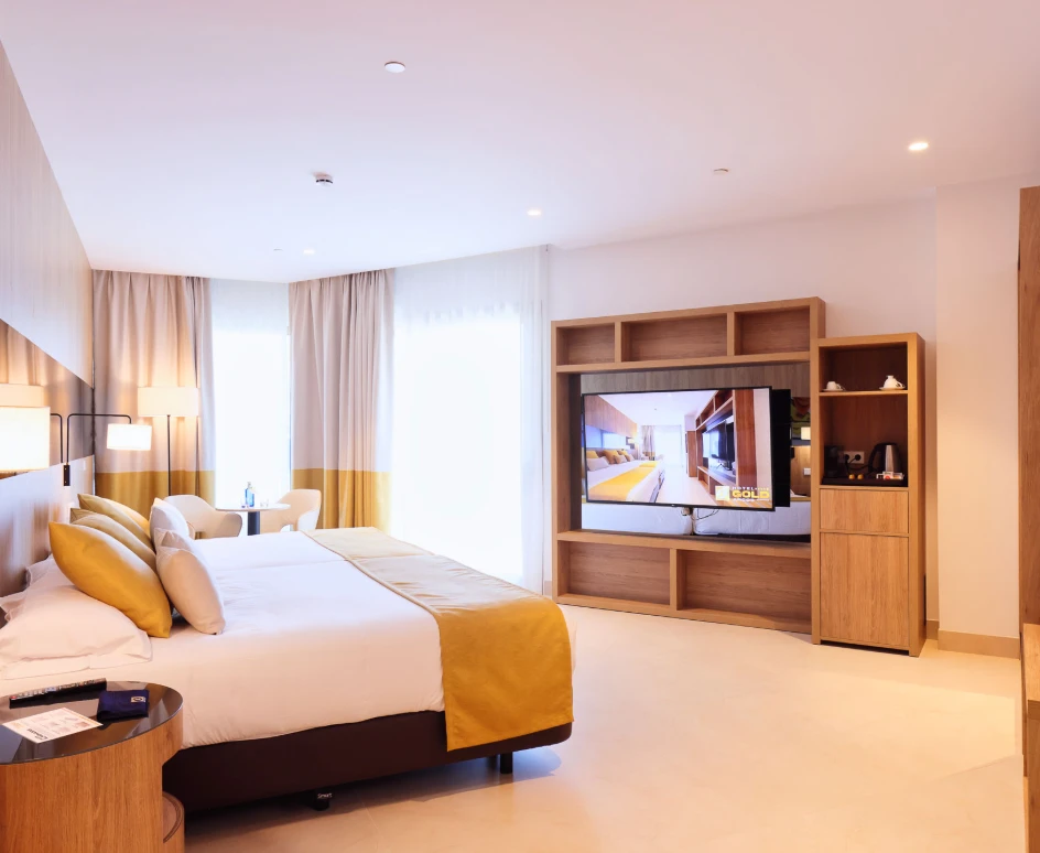 Habitaci&oacute;n de hotel moderna con cama y gran televisor.
