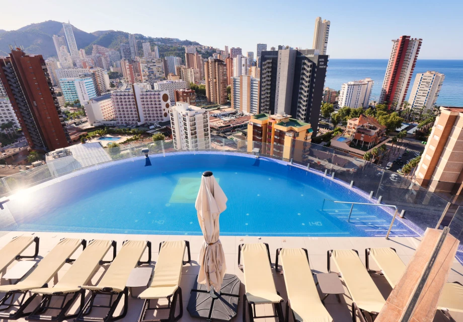 Piscina infinita con vistas a la ciudad y al mar al fondo.