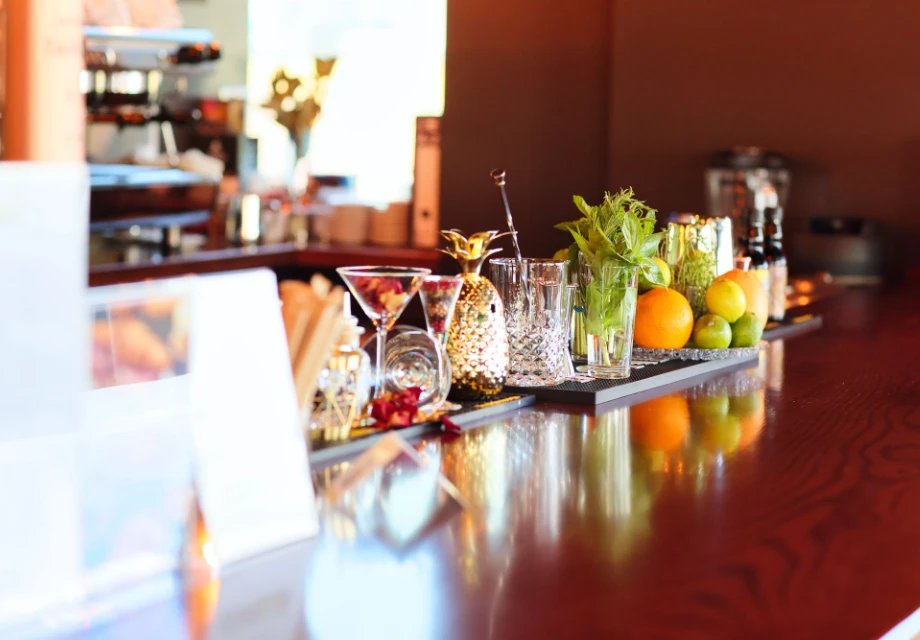 Barra de bar con frutas, vasos y adornos reflejados en la superficie.