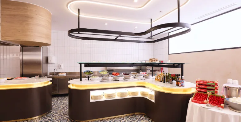 Buffet en restaurante moderno con platos, ensaladas e ingredientes variados.