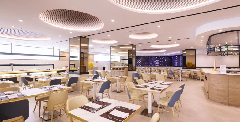 Restaurante moderno con mesas y sillas vac&iacute;as en un ambiente iluminado.