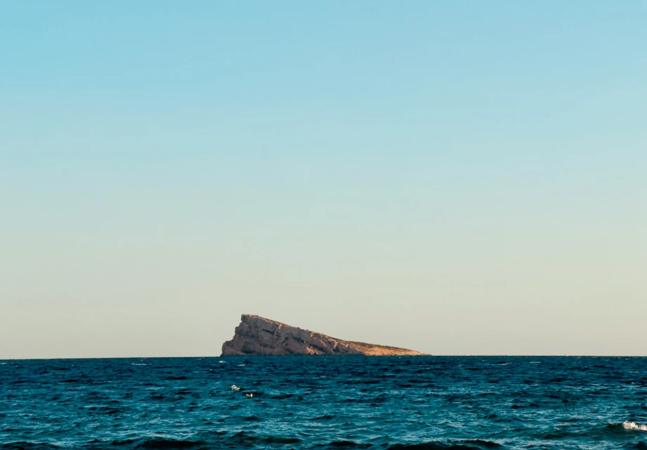 Isla rocosa en mar azul bajo un cielo despejado.