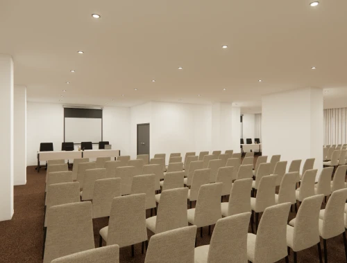 Empty conference room with rows of beige chairs facing a screen.