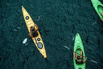 Personas remando en kayaks sobre aguas azul oscuro.