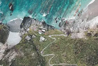 Vista a&eacute;rea de un sendero costero junto al mar con agua turquesa y rocas.