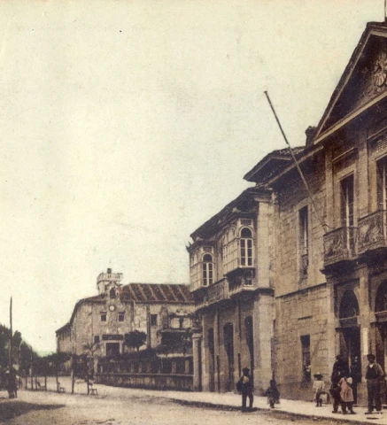 Calle antigua con edificios cl&aacute;sicos y algunas personas caminando.