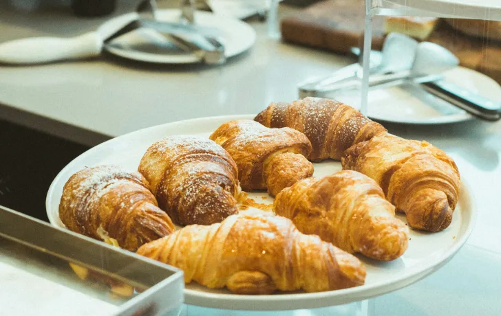 Croissants en un plato sobre una mesa, listos para servir.