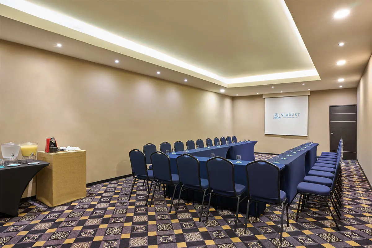Conference room with blue chairs, banquet tables, and projector screen.