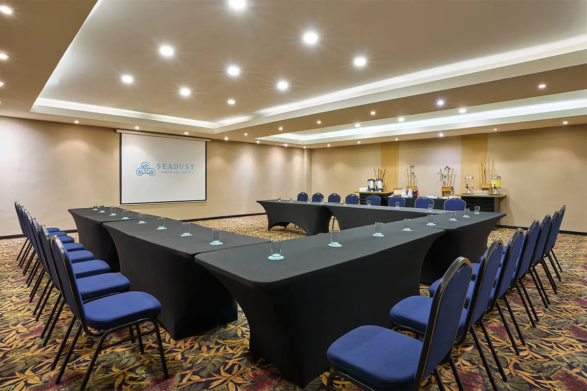 Modern conference room with U-shaped table, blue chairs, and projector screen