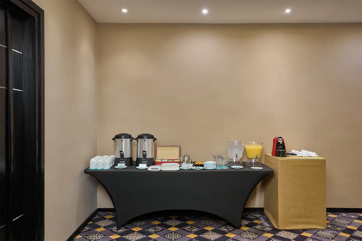 Hotel breakfast buffet table with coffee urns, juice dispensers, and cups