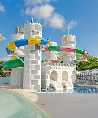 Colorful water slides and playful castle-shaped splash pool by a sunny pool