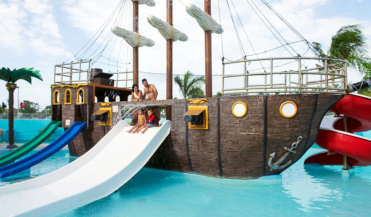 Resort water park ship-shaped slide with people in a pool