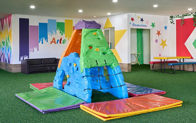 Kids&rsquo; indoor play area with colorful inflatable slide and art mural walls
