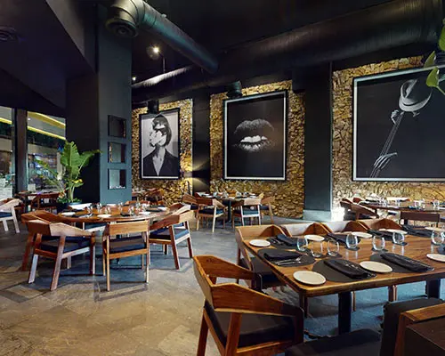 Modern restaurant interior with framed art and set wooden tables.