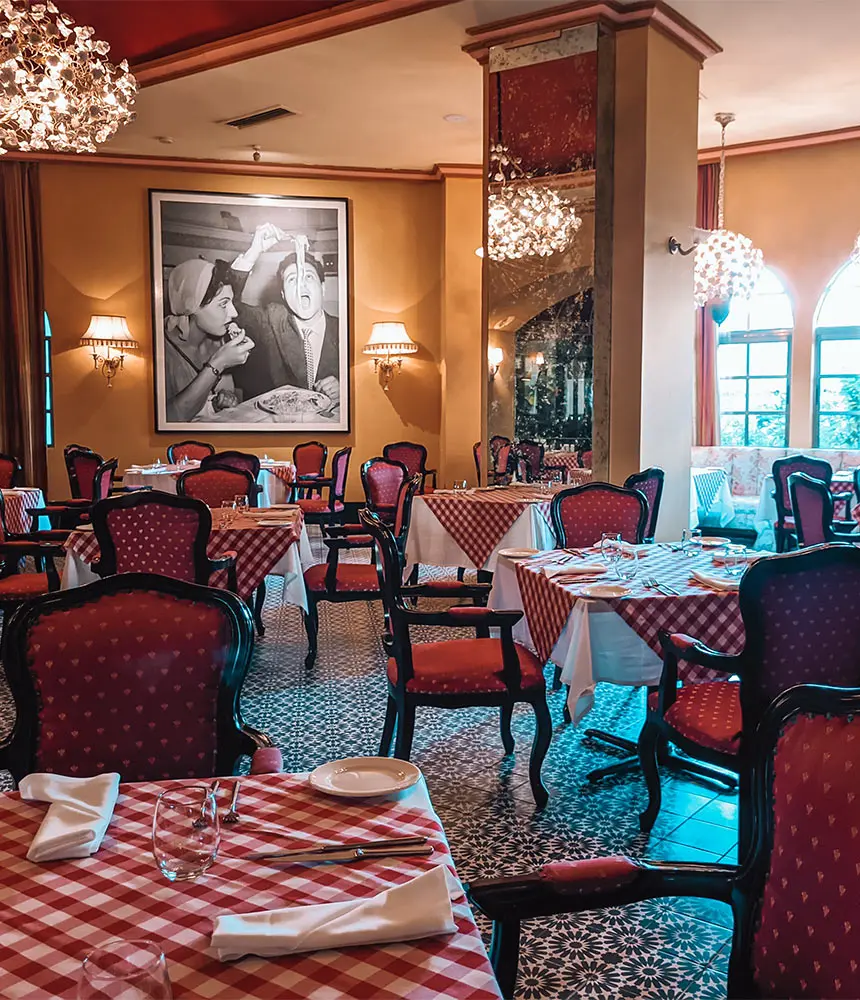 Elegant restaurant dining room with checkered tables and red chairs by windows