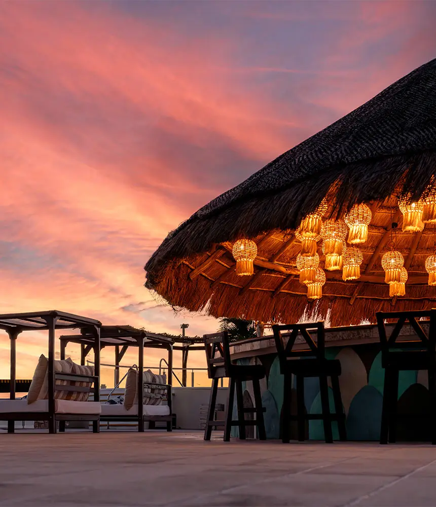 Thatched beachfront cabana with warm lantern lights at sunset
