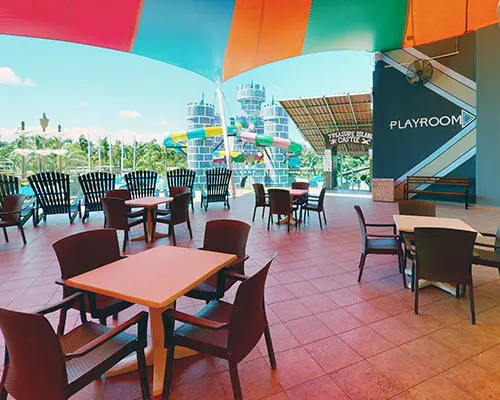 Outdoor patio with colorful inflatable canopy and chairs near a playroom sign