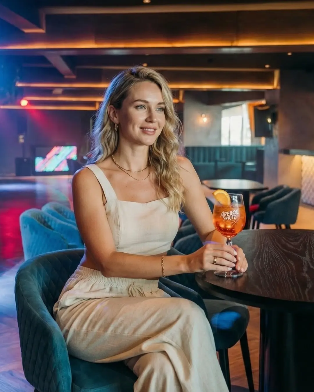 Woman in a white dress holding a cocktail glass in a bar lounge