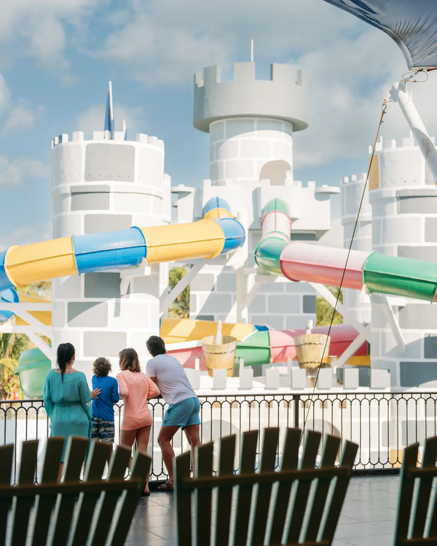 People watch colorful water slides at a white amusement park tower.