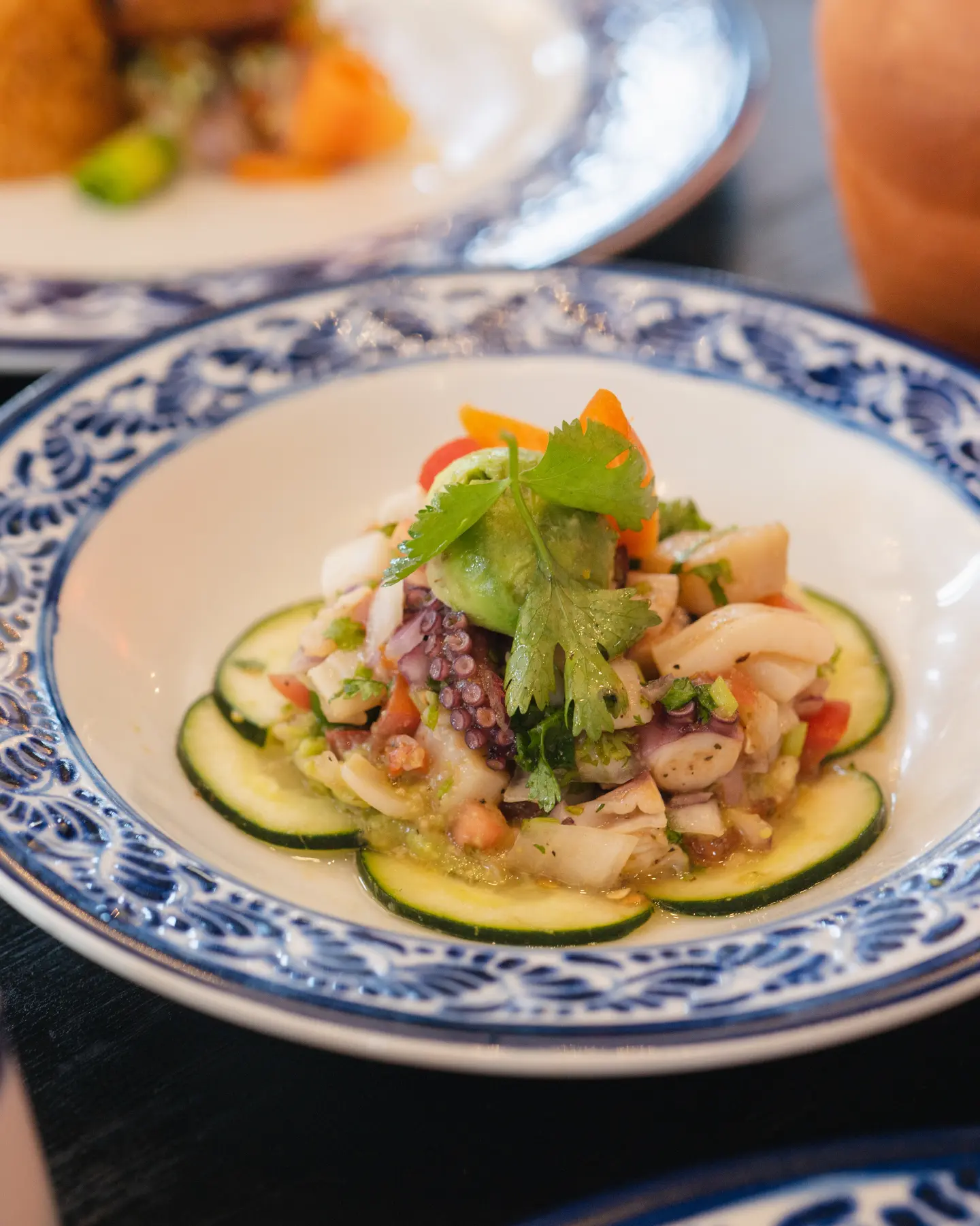 Cucumber and octopus salad with avocado, greens, and diced vegetables on a plate