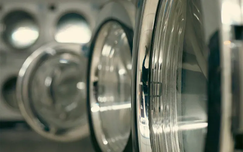 Close-up of clear glass bottles and a reflection in a dim store aisle.